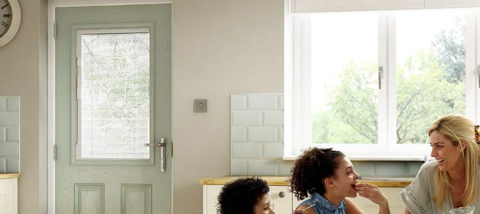 Family in a kitchen enjoying their new composite door, fitted by Paradise Windows