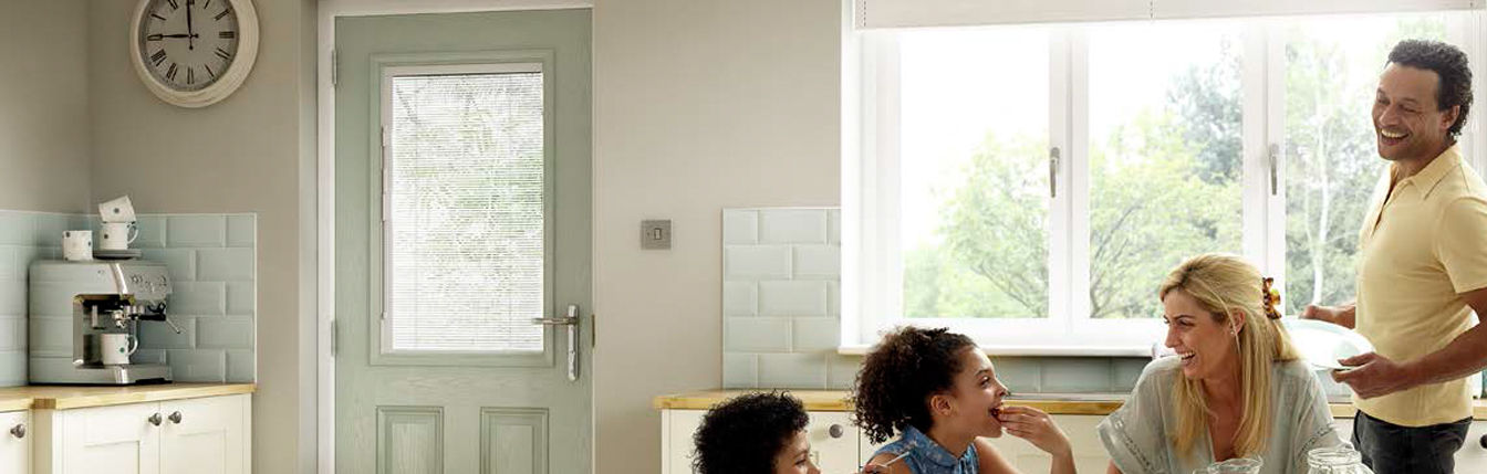 Family in a kitchen enjoying their new composite door, fitted by Paradise Windows